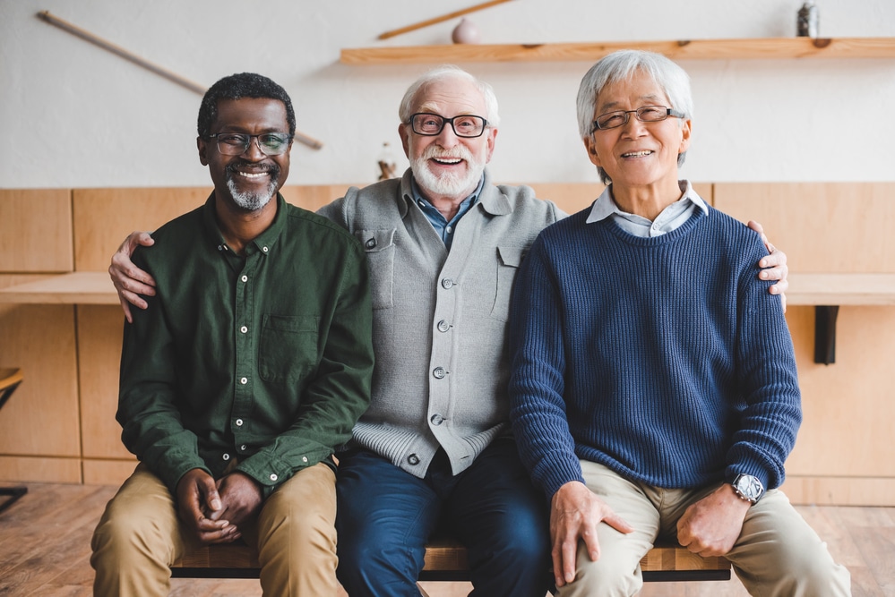three senior men sitting next to each other smiling