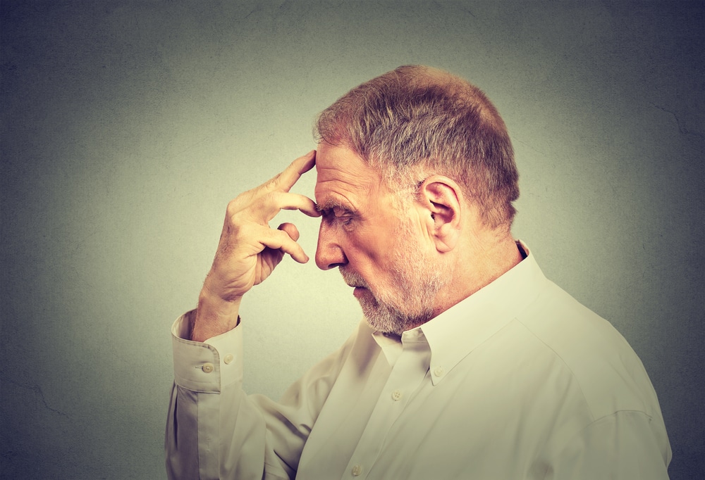senior man with head down with head in hand, appears distraught. Understanding the different types of dementia