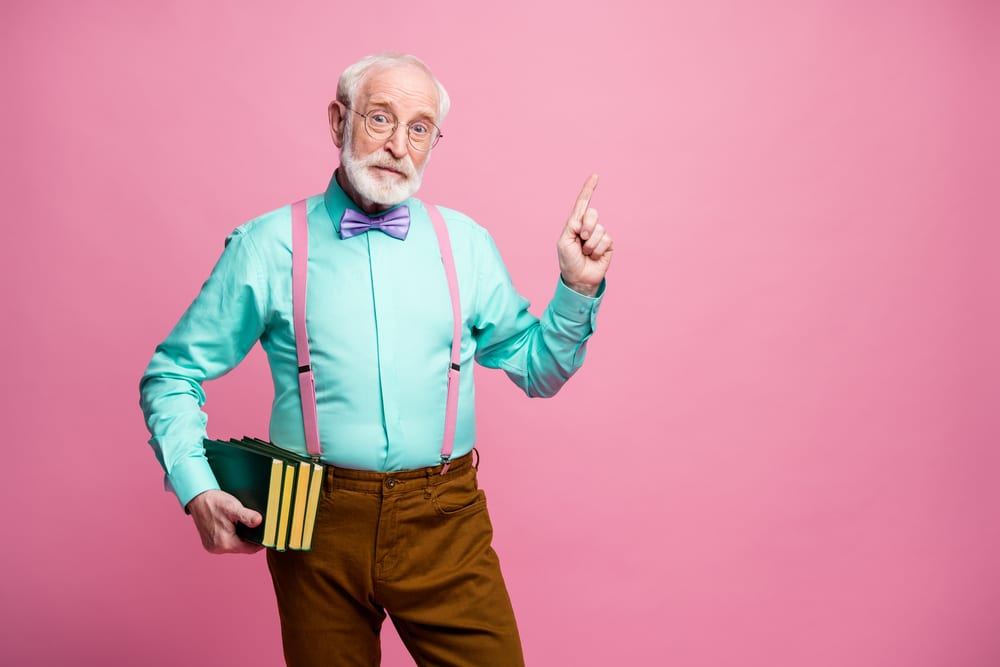 Photo of funny aged grandpa teacher, efficacy of brain training for seniors hold books lecturer university, college direct finger empty space black board wear specs shirt suspenders bow tie pants isolated pink pastel color background