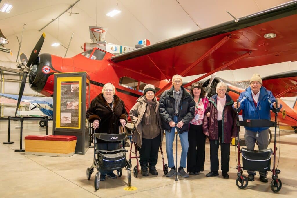 Baxter Senior Living | Assisted living residents in alaska standing in front of a plane